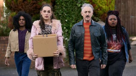 A group of four people walk down the middle of a street