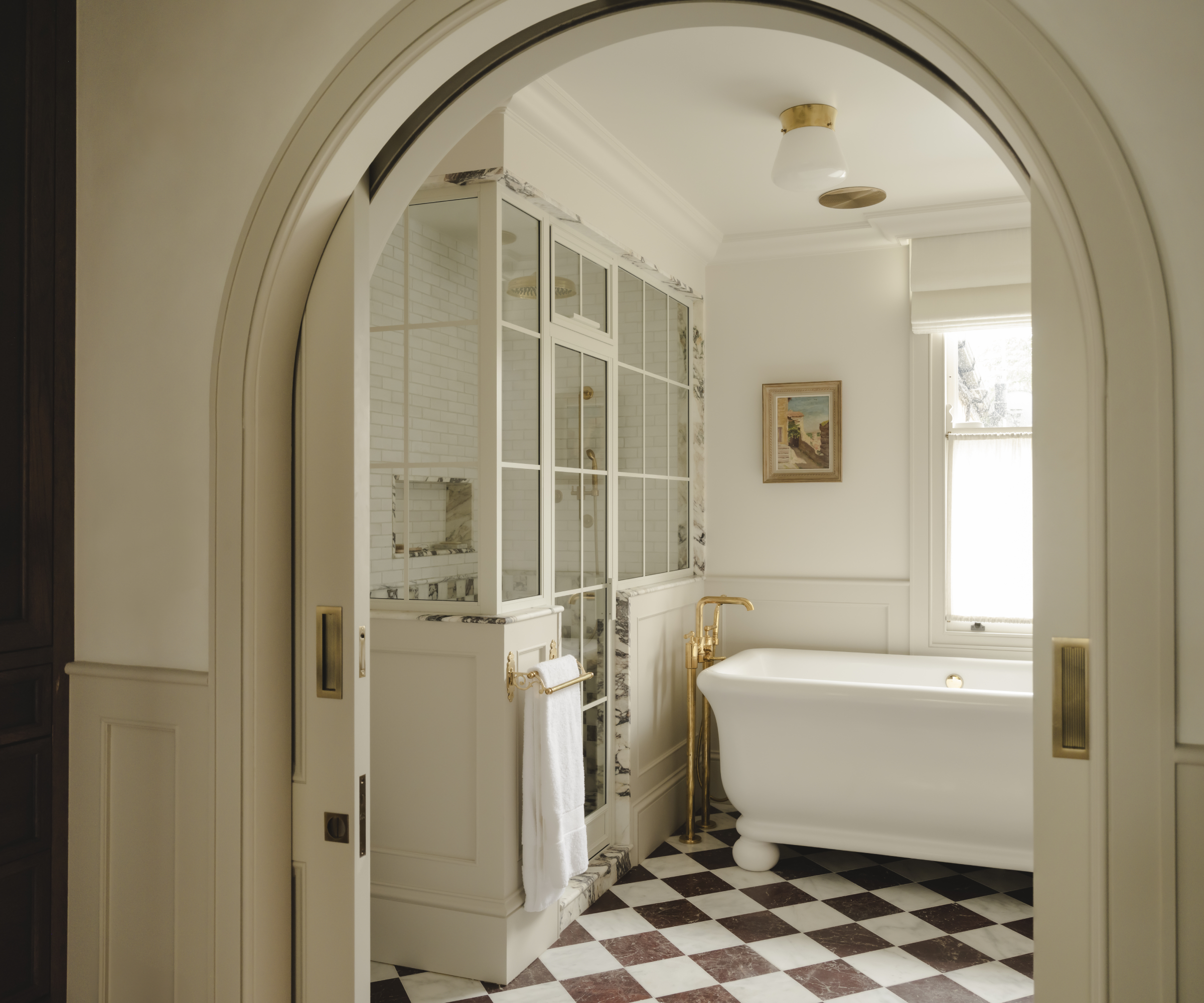 arched entrance into bathroom with conservatory style shower room tiled floor and freestanding bath