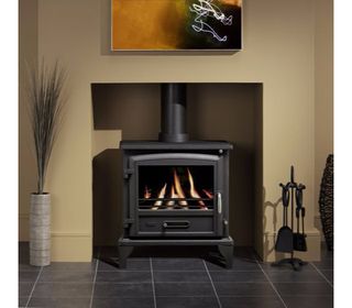 Fire in woodburning stove in living room with cream walls with artwork fixed to the wall above