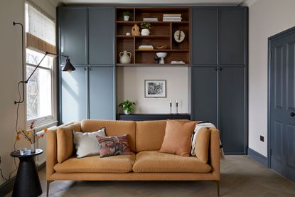 Blue living room with orange sofa and built in storage unit