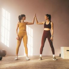 Progressive overload: Two women high fiving after a workout