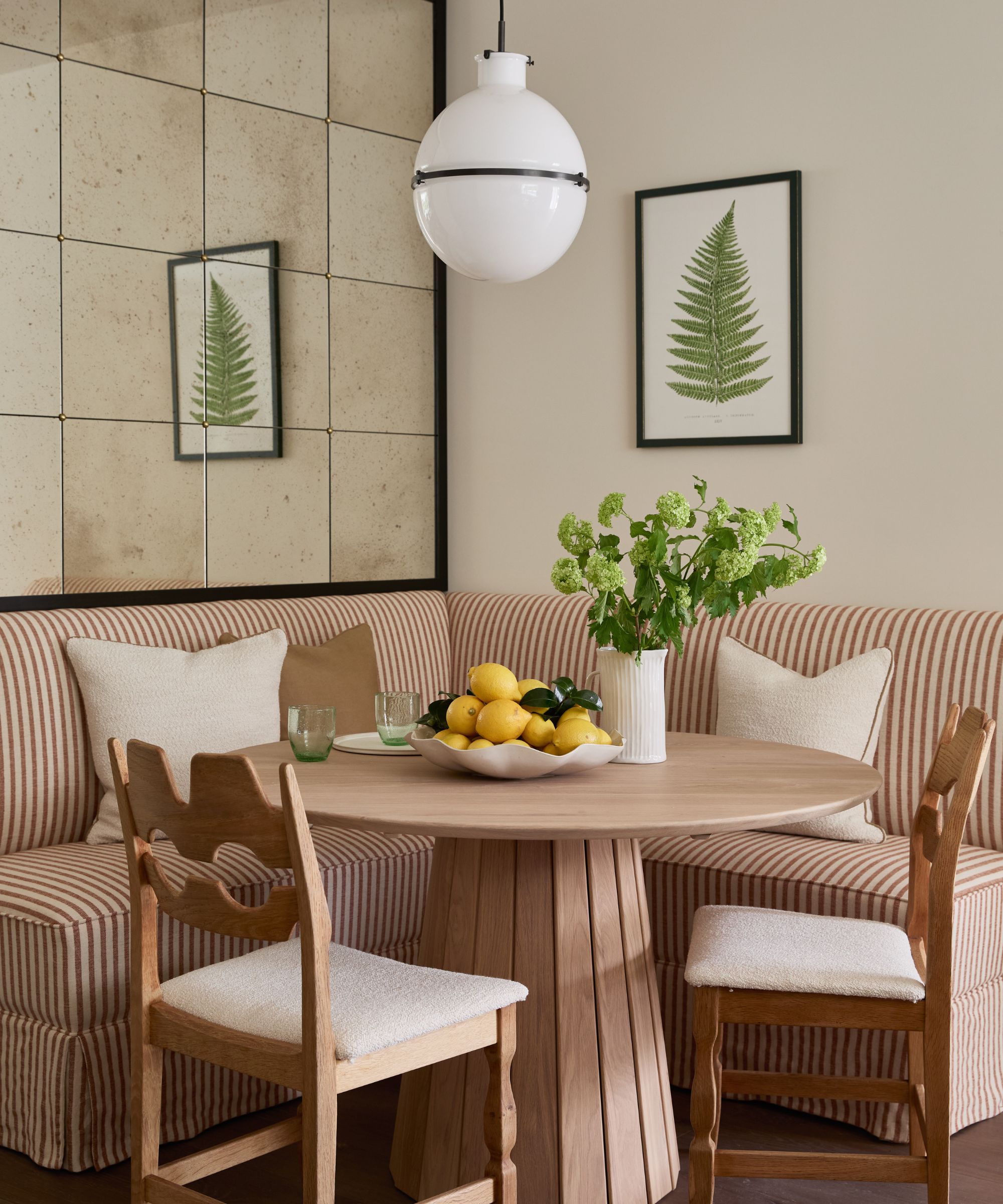breakfast nook with red striped upholstered bench, wooden table and two chairs