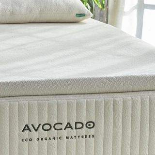 Corner of the Avocado Eco Organic Mattress Topper on a bed.