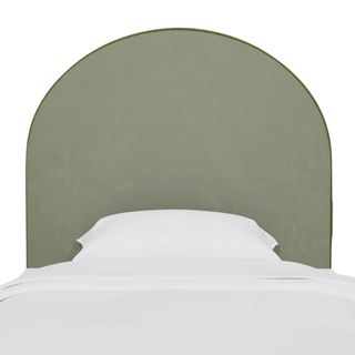 An olive green velvet arched headboard above a bed with all white bedding