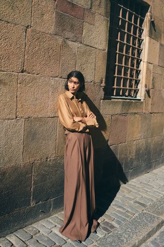 Woman wears satin shirt and tailored trousers