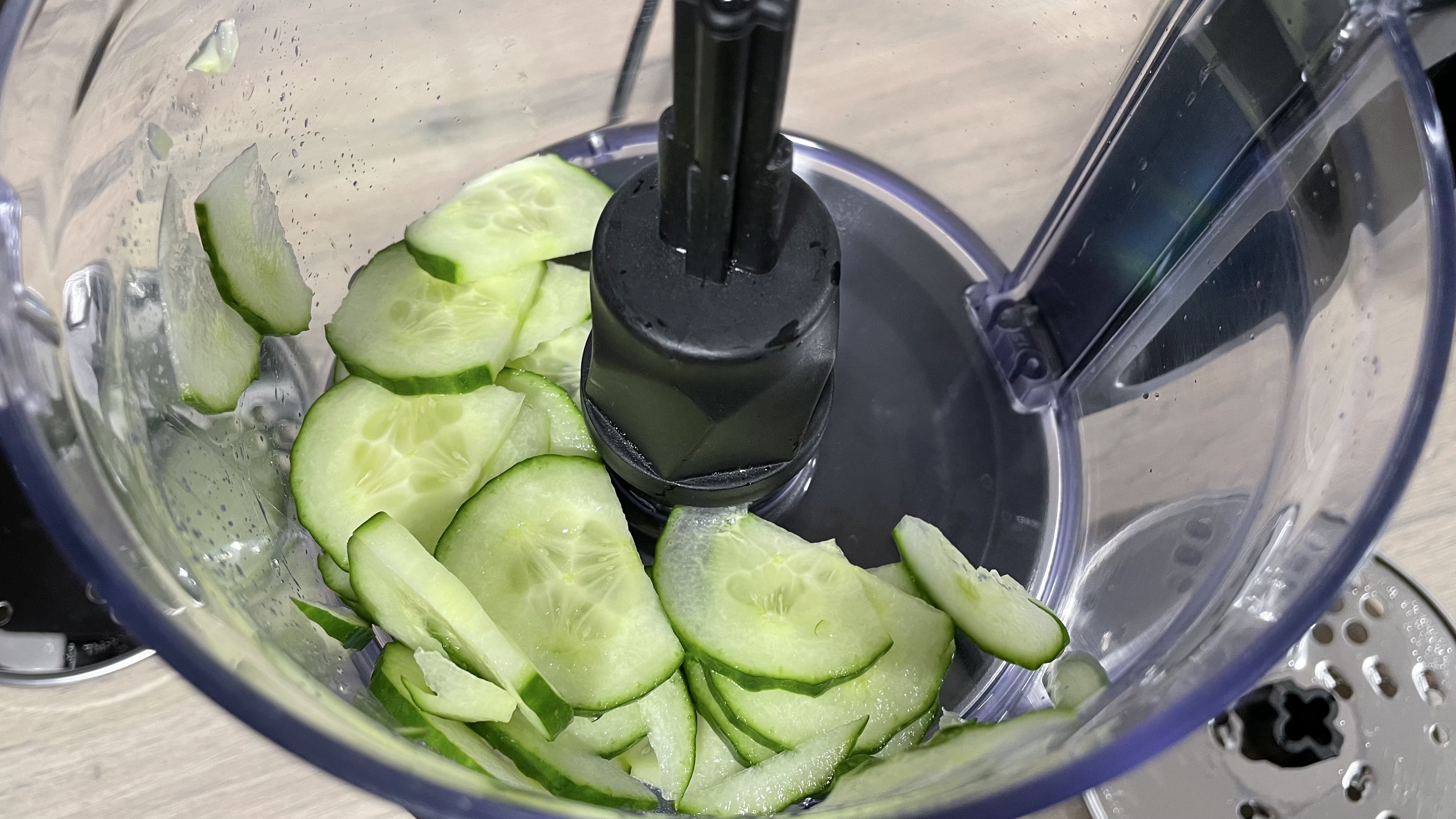 A close up of sliced cucumber inside the KitchenAid 7 cup food processor work bowl.