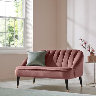 living area with pink sofa and pink wall and wooden floor