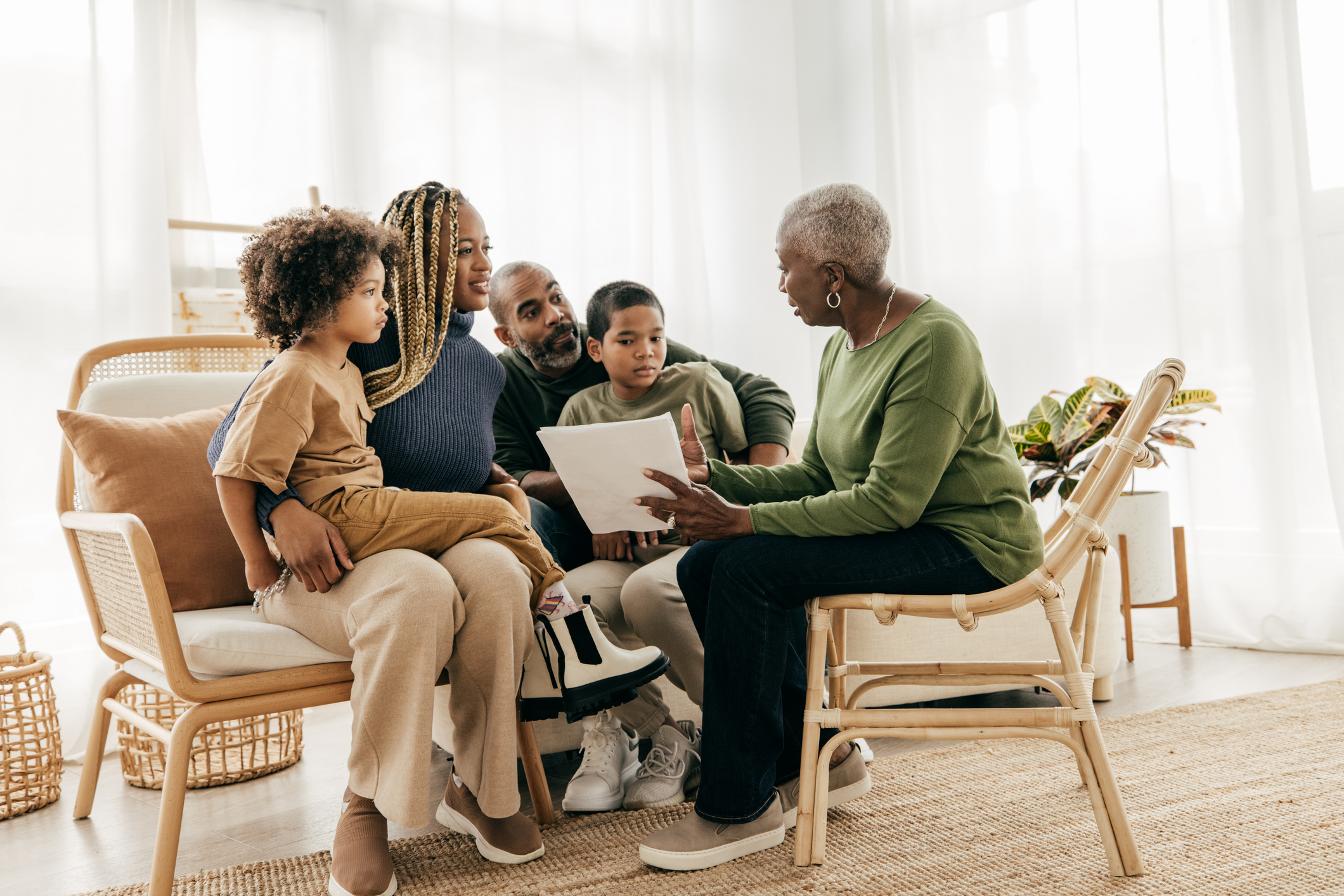 A senior woman reviews financial paperwork with her family in her living room.