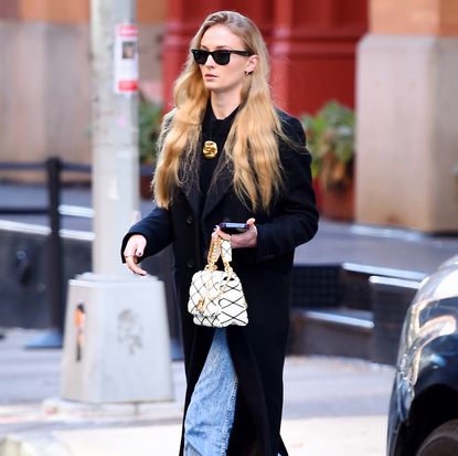 Sophie Turner in a coat, jeans, and chunky chain-link loafers