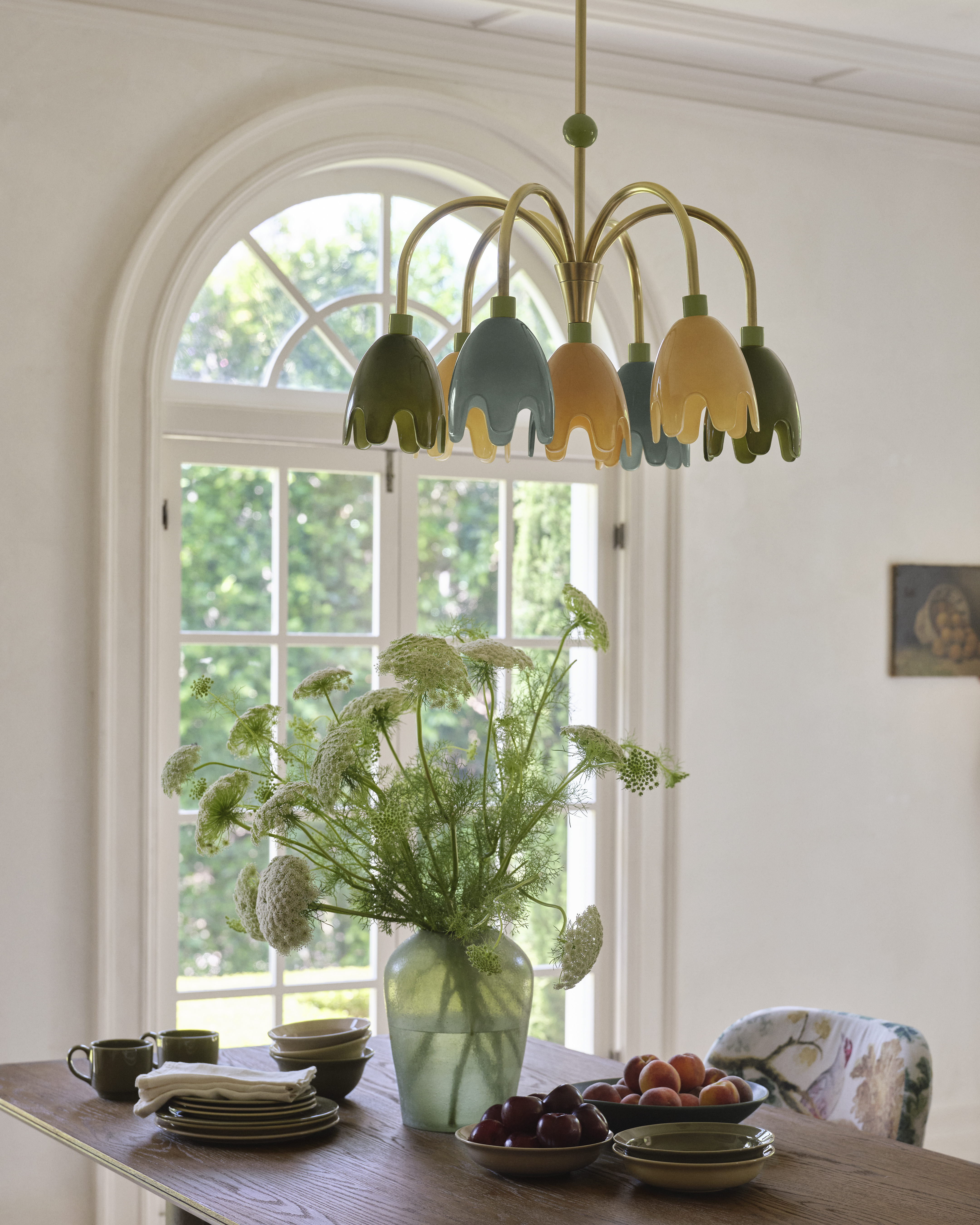 Multi-color, multi-shade chandlier hanging over a sunlit breakfast nook, looking out onto an arched window