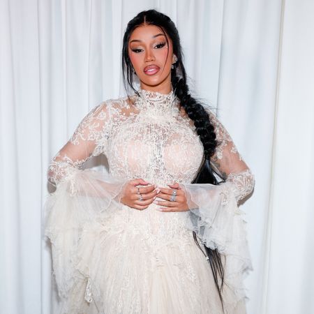 A woman with a braided hairstyle wearing a sheer, white lace top