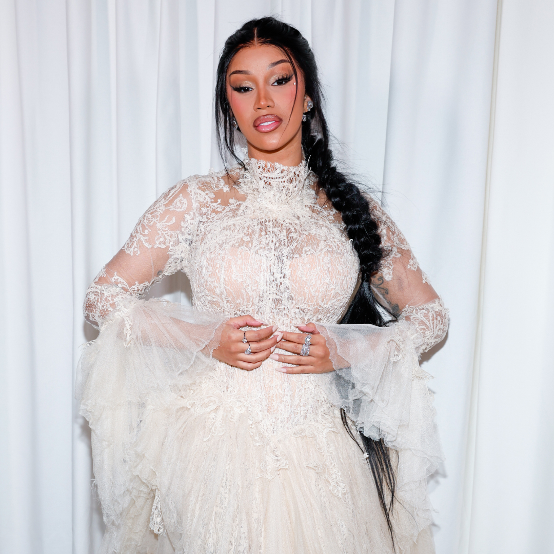 A woman with a braided hairstyle wearing a sheer, white lace top