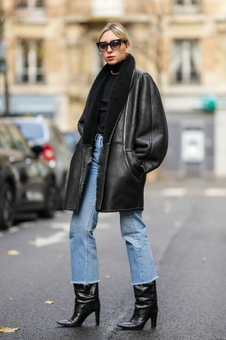 a woman wearing a leather jacket and denim trousers