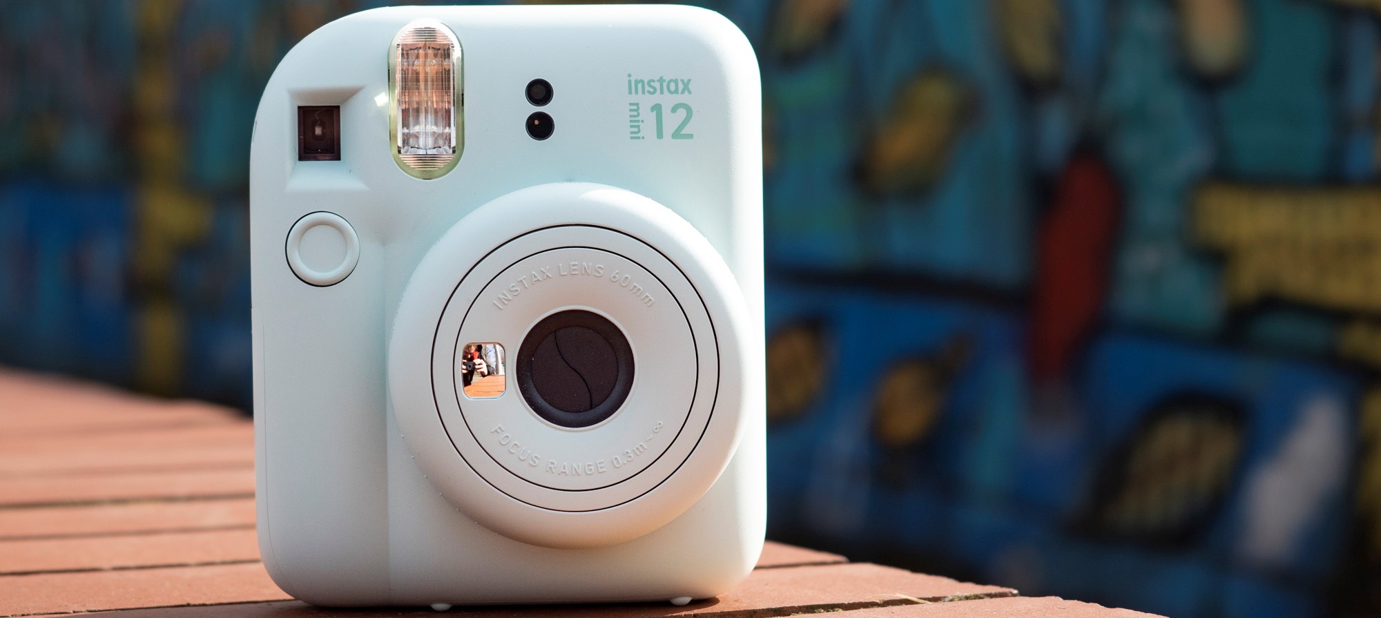 Instax Mini 12 on a brick wall in front of graffiti