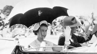 3/20/1954-Townsville, Australia- The top was back so the crowds could see Queen Elizabeth II and the Duke of Edinburgh as they drove through Townsville, Queensland, recetly, so Liz hoisted a sunshade with one hand and waved to the crowds with the other. Well, they say the sun never sets on the British empire...
