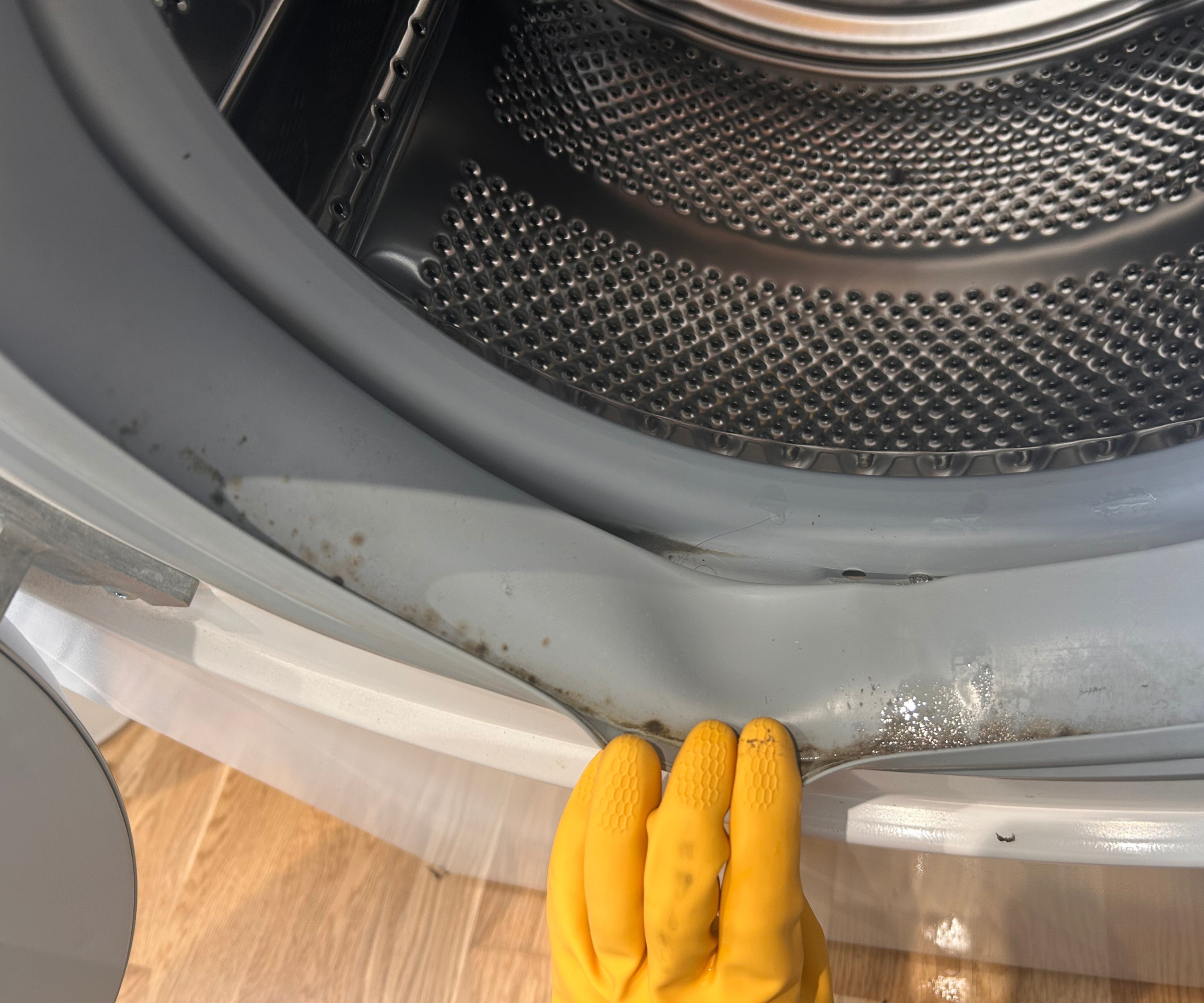 Rubber gloved hands are pulling the rubber back into Megan's washing machine
