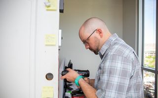 A man drills holes in his front door to fit a new smart lock