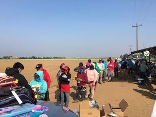 farm workers wait in line for donated school supplies