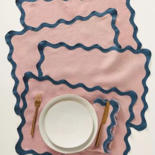 Pink scalloped linen placemats on white background