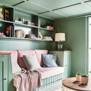 Soft sage green living room with built in sofa and shelving and painted panelled ceiling