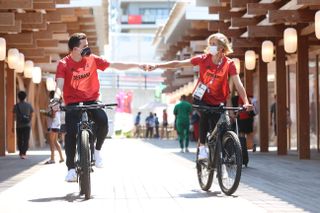 olympic athletes fist bump and ride bikes