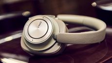 DALI IO-12 headphones in 2025's new colour option, Mocha Grey. They're sitting on a dark wooden surface.