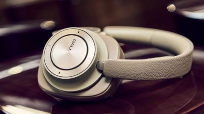 DALI IO-12 headphones in 2025's new colour option, Mocha Grey. They're sitting on a dark wooden surface.