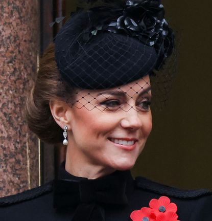 Kate Middleton wearing a black hat and coat smiling 