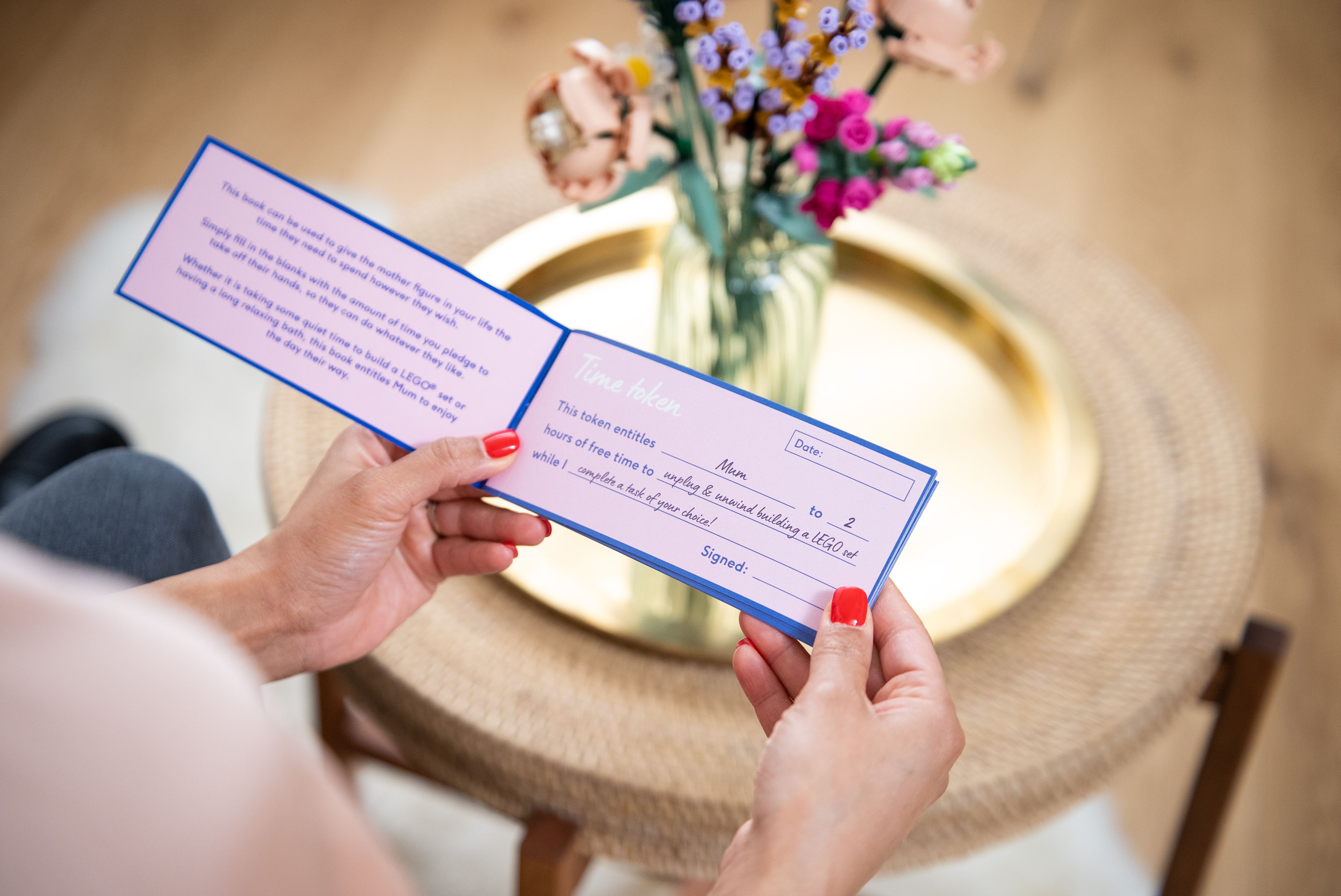 A woman holds the Time Tokens for Mum booklet, available free this Mother's Day from Moonpig with any purchase of Lego.