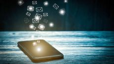 smartphone on wooden table with tiny envelopes hovering above screen