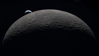 A view of the moon in the foreground with a small Earth in the background.