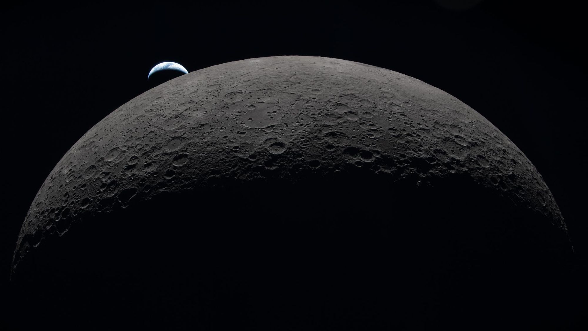 A view of the moon in the foreground with a small Earth in the background.