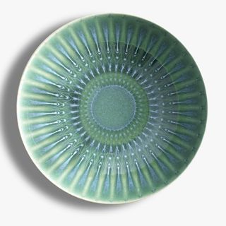 A green patterned plate photographed against a white background