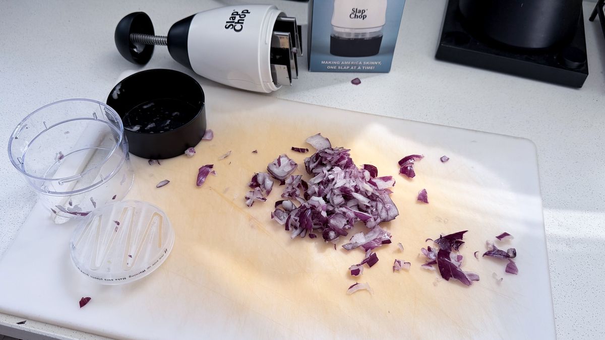 Onions on a chopping board, cut on the Slap Chop with the device next to them