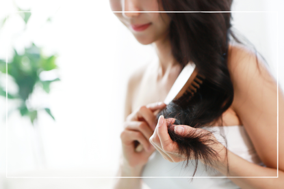 a close up of a woman brushing her hair - one of our tips for healthy hair