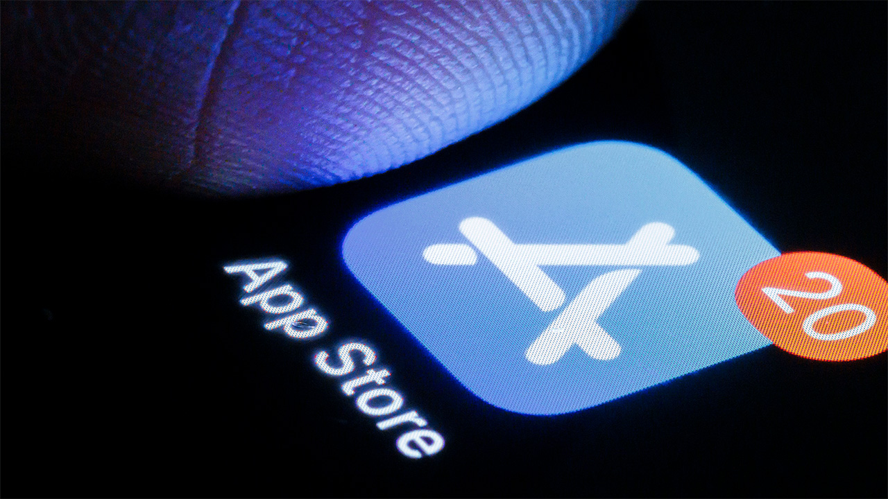 Apple App Store icon displayed on iPhone with notification symbol and close up of a person's finger