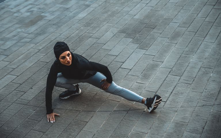 Woman bending into a side lunge outside