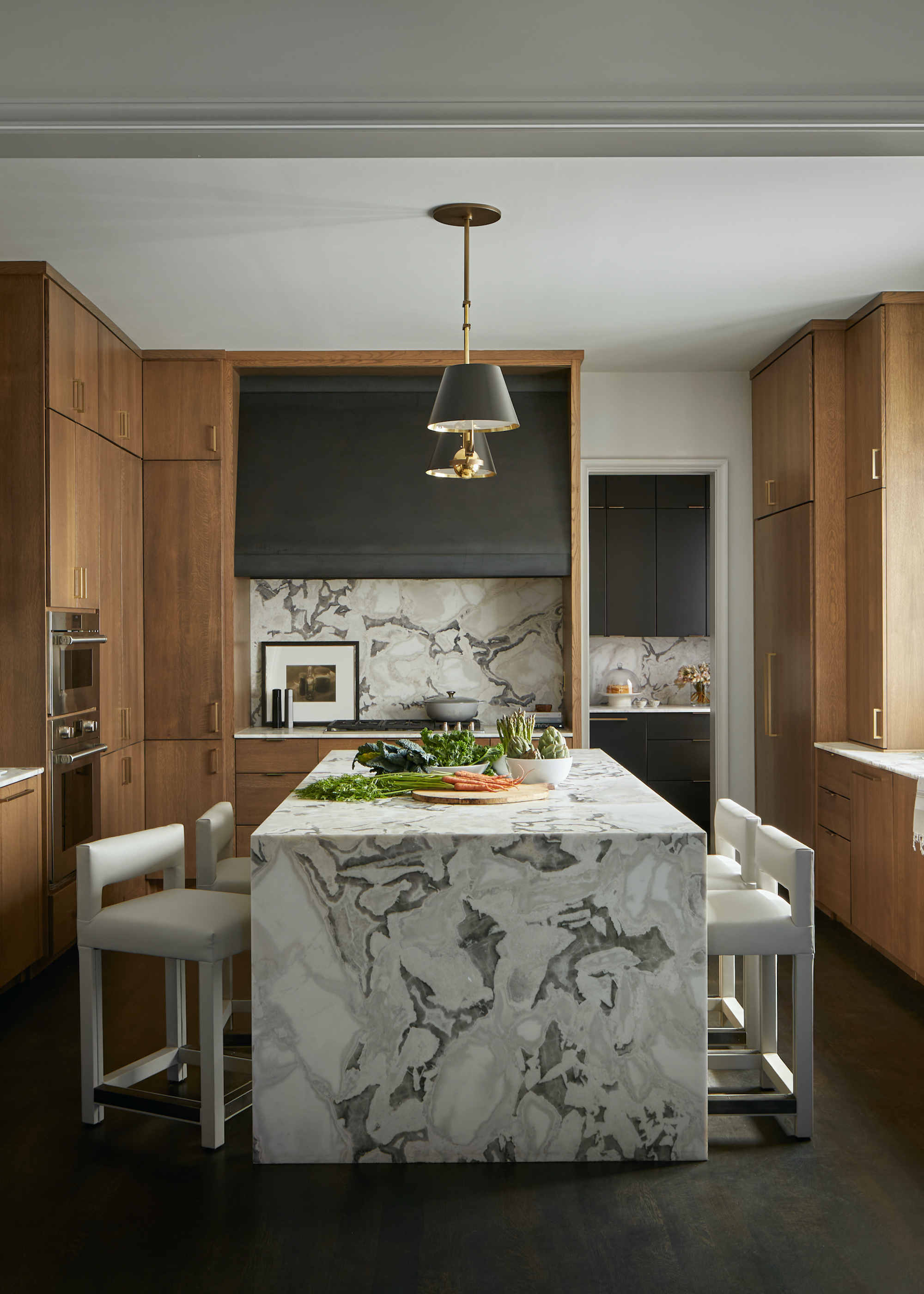 wood kitchen with island heavily veined stone and stools on both sides
