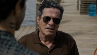 Joaquim de Almeida stands in front of Jake Gyllenhaal in conversation wearing sunglasses in Road House.