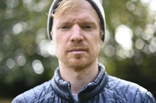 Head and shoulder portrait, outdoors, shallow depth of field, dappled light through tree leaves