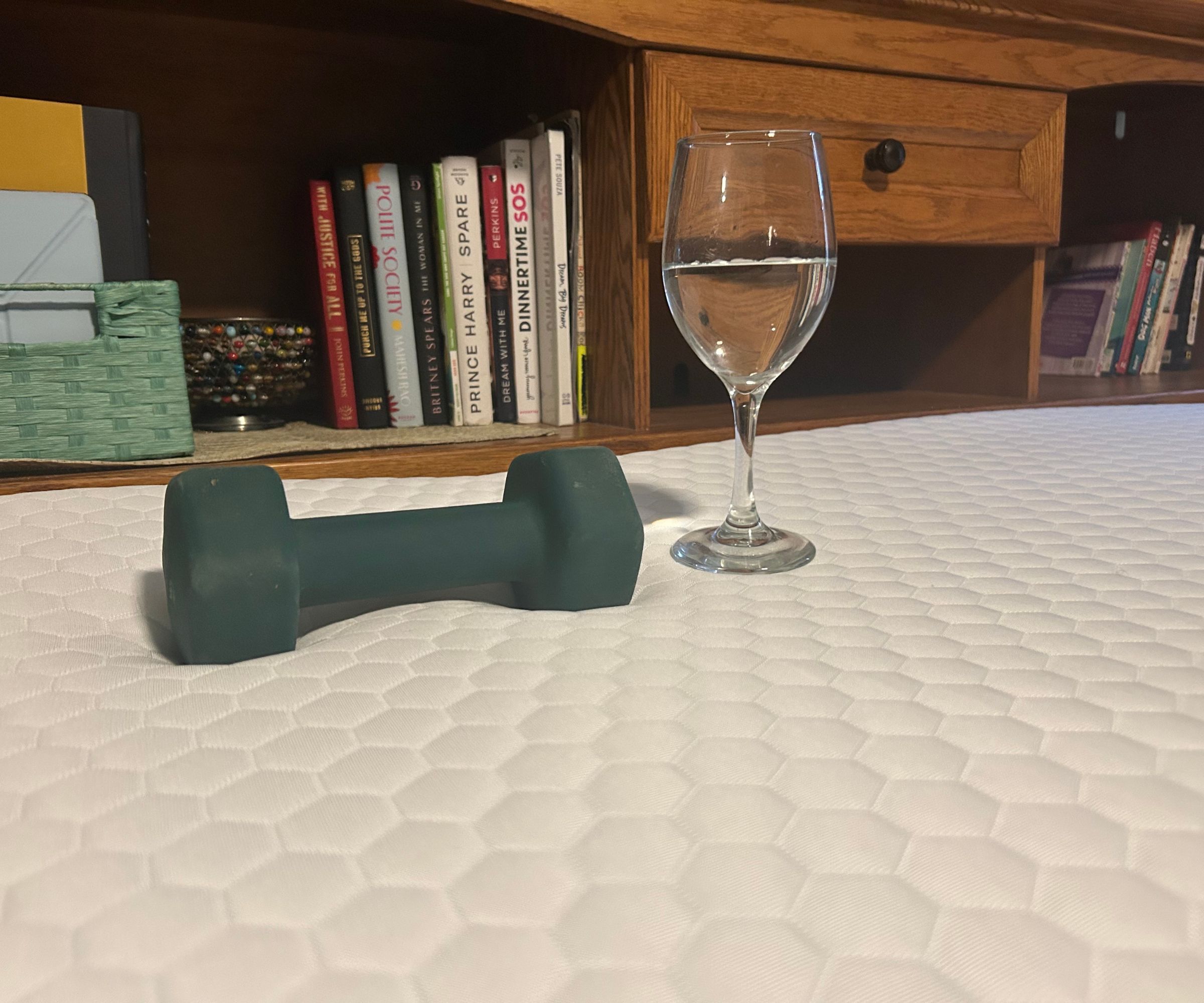 A wine glass and a dumbbell resting on the Helix ErgoAlign Mattress Topper.