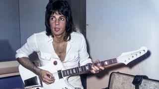 15th June 1974: Australian-born actor and pop singer Rick Springfield sits on the arm of a couch, playing his electric guitar backstage before a concert at Knotts Berry Farm, Anaheim, California. He wears patchwork jeans and an open-collared white shirt. 