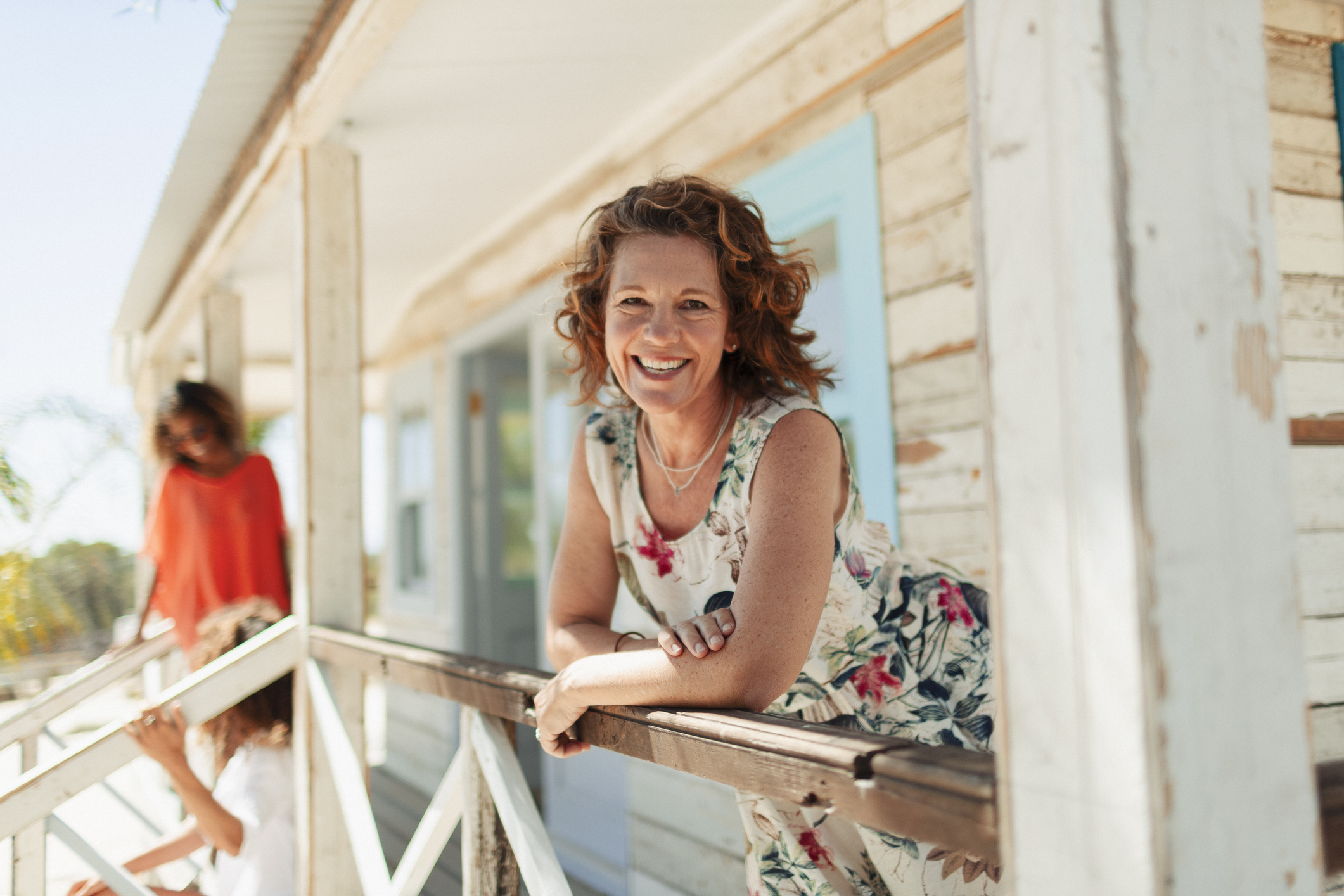 Portrait of a smiling, confident woman in her 50s on a sunny beach hut patio.
