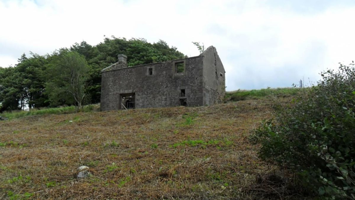 An old stone cottage with no roof on a sloped site