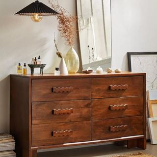 Urban Outfitters Alonzo Dresser with trinkets on top against a white wall.
