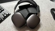 Apple AirPods Max ontop of their case on a grey desk