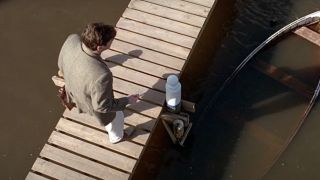 Jim Carrey looks over a rowboat that's sunk into the water.