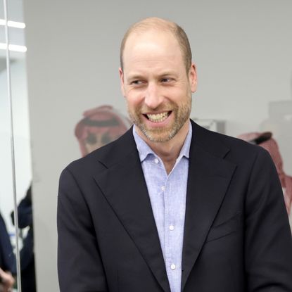 Prince William wearing a suit and laughing standing in a room with gamers