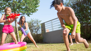 Image of three kids playing with water pistols next to an inflatable pool
