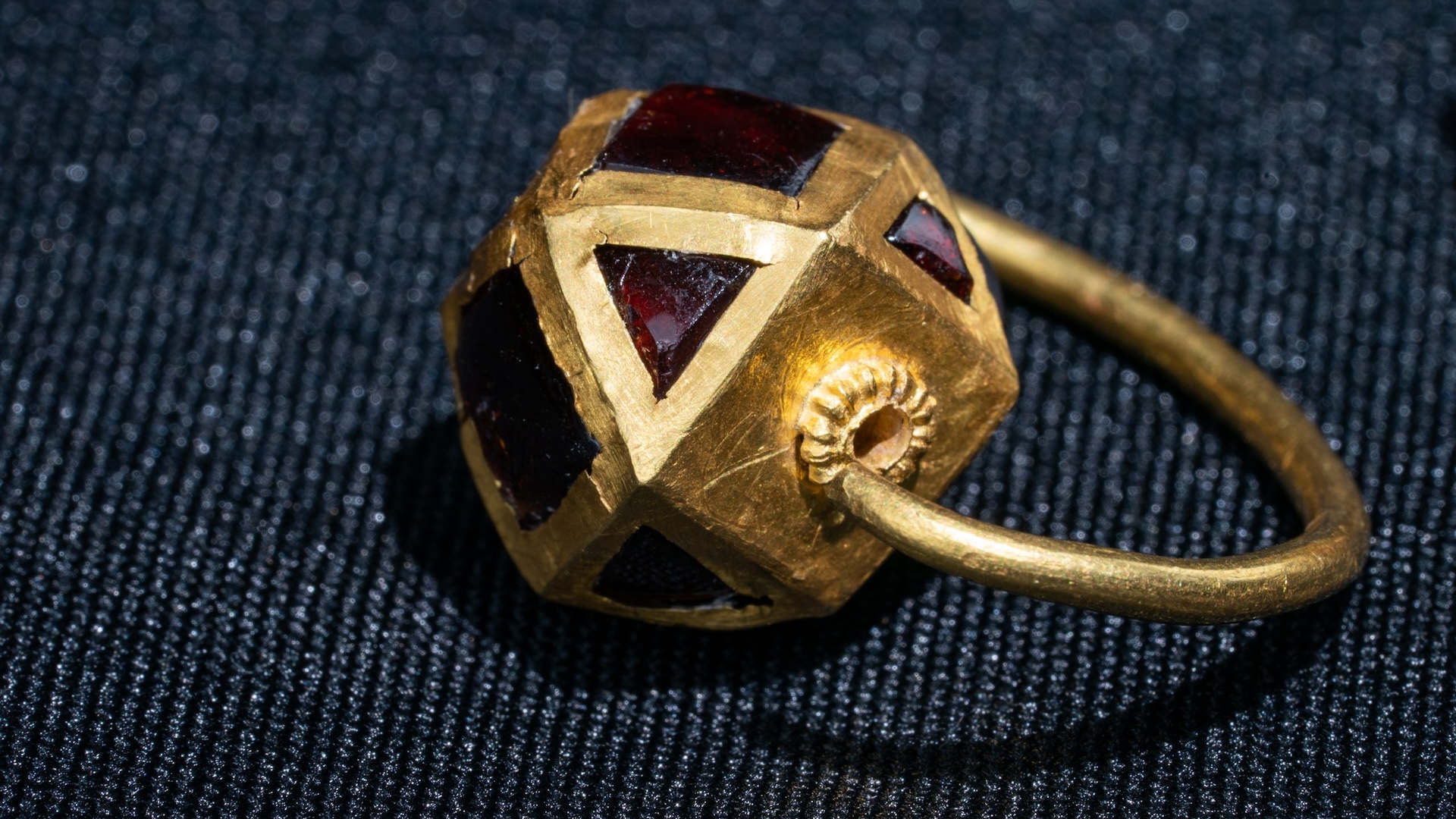 A close-up of a gold ring with red jewels